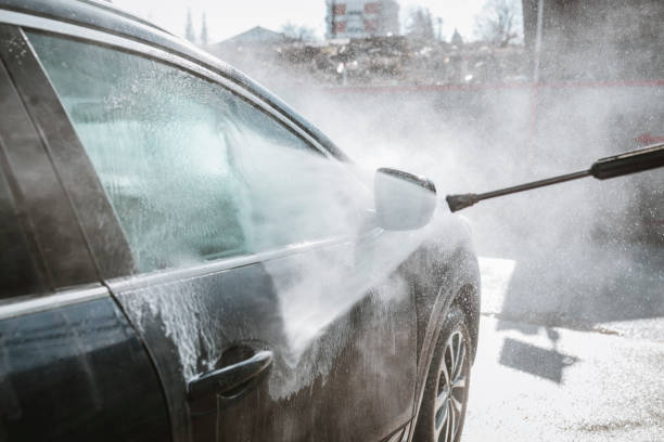 washing his car under high pressure water outdoors
